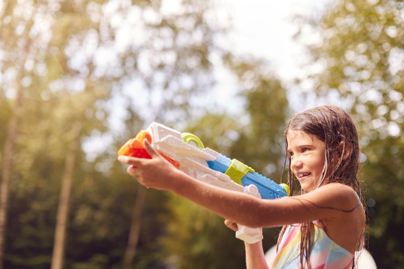 Ein Mädchen, dass mit einer Super Soaker Wasserpistole spielt.